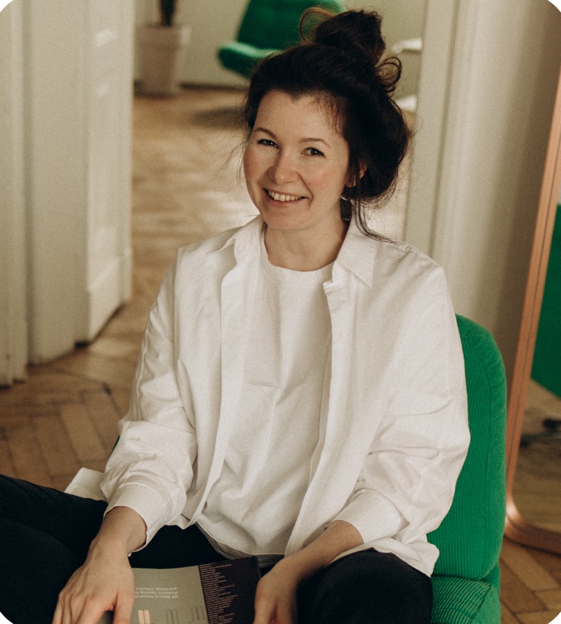 Karina smiling in a green armchair